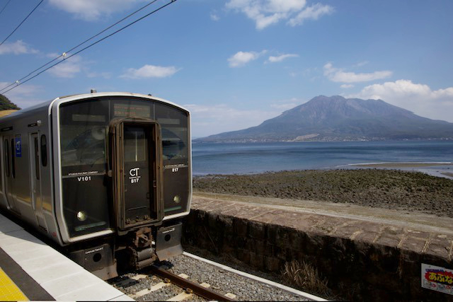 Místní vlak a sopka Sakurajima v pozadí
